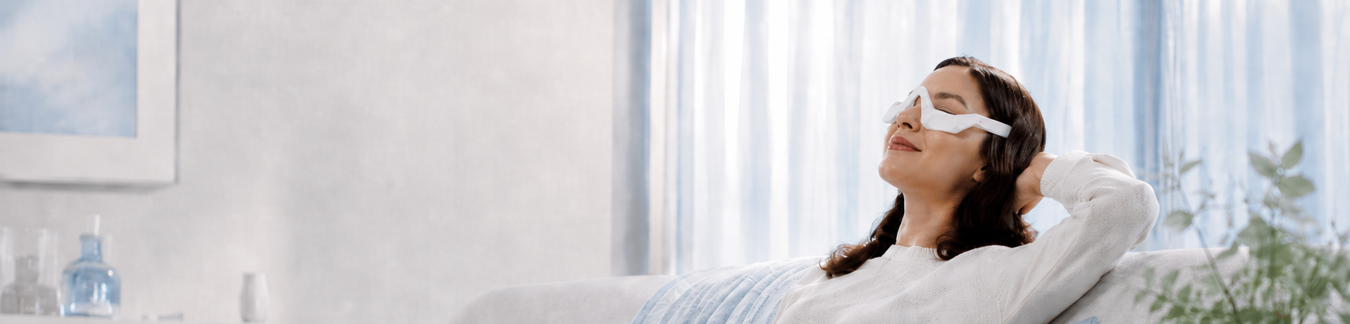 Woman relaxing with the LumaRest Eye Massager on the sofa